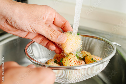 man rinses some pineberries with tap water