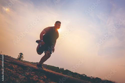 Silhouette of overweight man running sprinting on road. Fat man runner jogging at outdoor workout. Exercise concept for weight control. photo