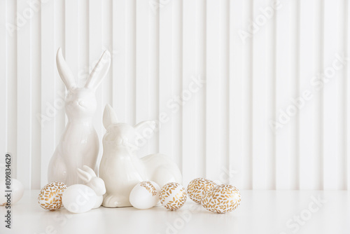 Easter rabbits figurines and eggs on white background. Easter celebration concept. Copy space. Front view