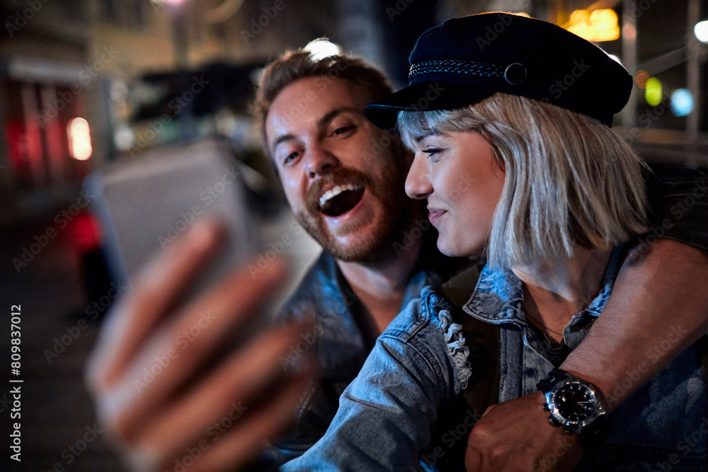 Happy couple taking a selfie at night on a city street Happy couple taking a selfie at night on a city street