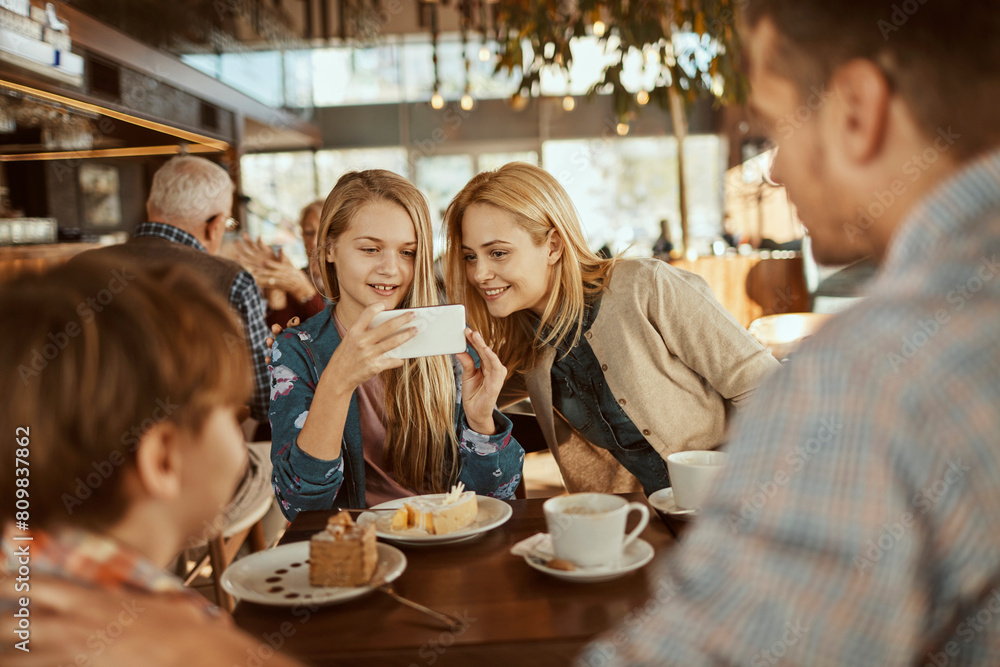 Happy young family sitting in cafe decorated for the Christmas holidays Happy young family sitting in cafe decorated for the Christmas holidays