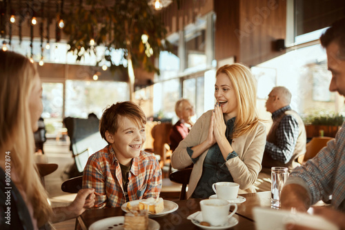 Happy young family sitting in cafe decorated for the Christmas holidays photo