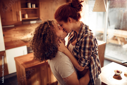Romantic couple kissing in cozy home kitchen photo