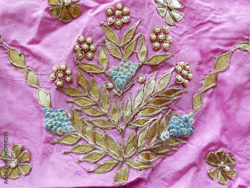 Intricate golden gotta patti floral motif with blue tikki and pearl embroidery on pink silk fabric photo