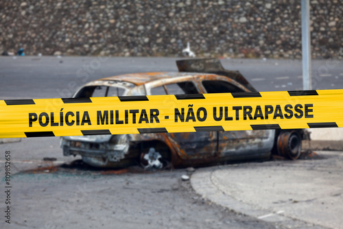Brazilian military police tape in front of a burnt car