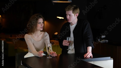 Young couple sitting in a restaurant with glasses of champagne while quarreling. Lifestyle  relationship  date concept. 