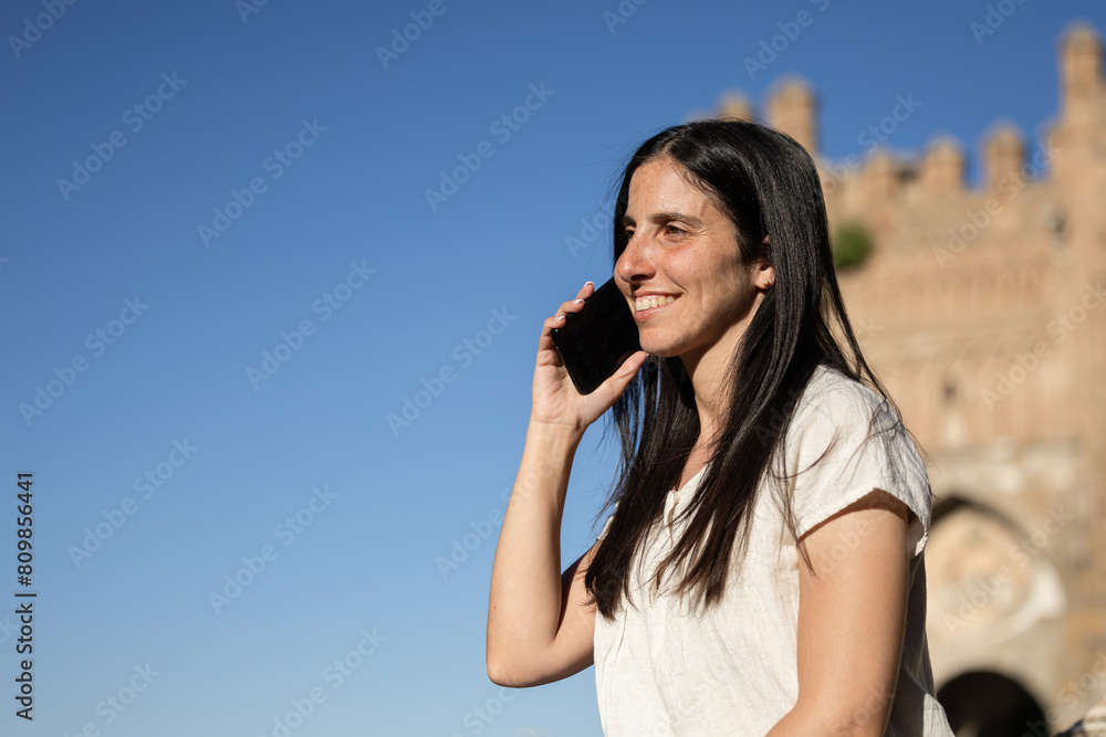 Woman talking on the phone while smiling. Happy woman talking on mobile phone. Girl smiling while she has a conversation on the mobile phone. Woman talking on the phone while smiling. Happy woman talking on mobile phone. Girl smiling while she has a conversation on the mobile phone.