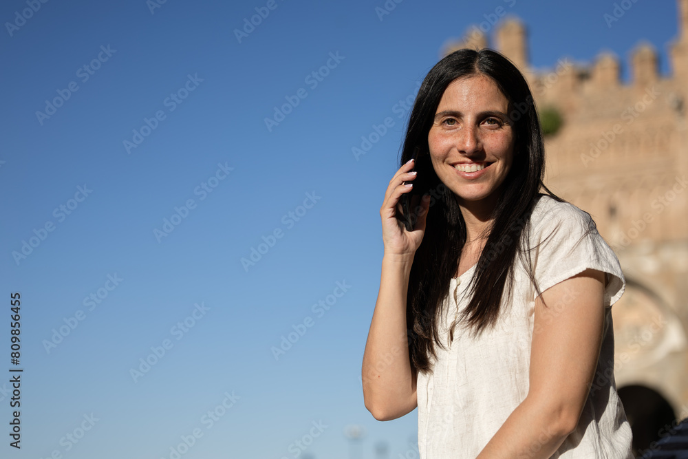 Woman talking on the phone while smiling. Happy woman talking on mobile phone. Girl smiling while she has a conversation on the mobile phone. Woman talking on the phone while smiling. Happy woman talking on mobile phone. Girl smiling while she has a conversation on the mobile phone.