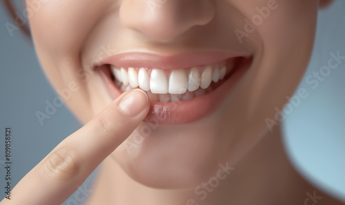 Close-up of a smiling woman pointing at her clean  white teeth.  