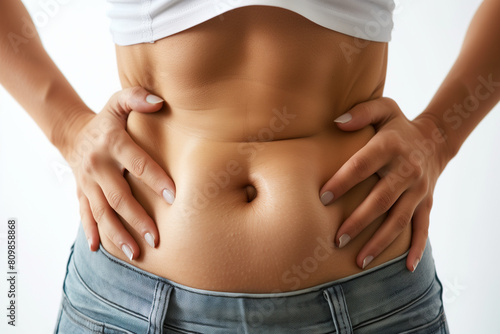 Close-up of woman's waist and abs with hands on hips, white background 