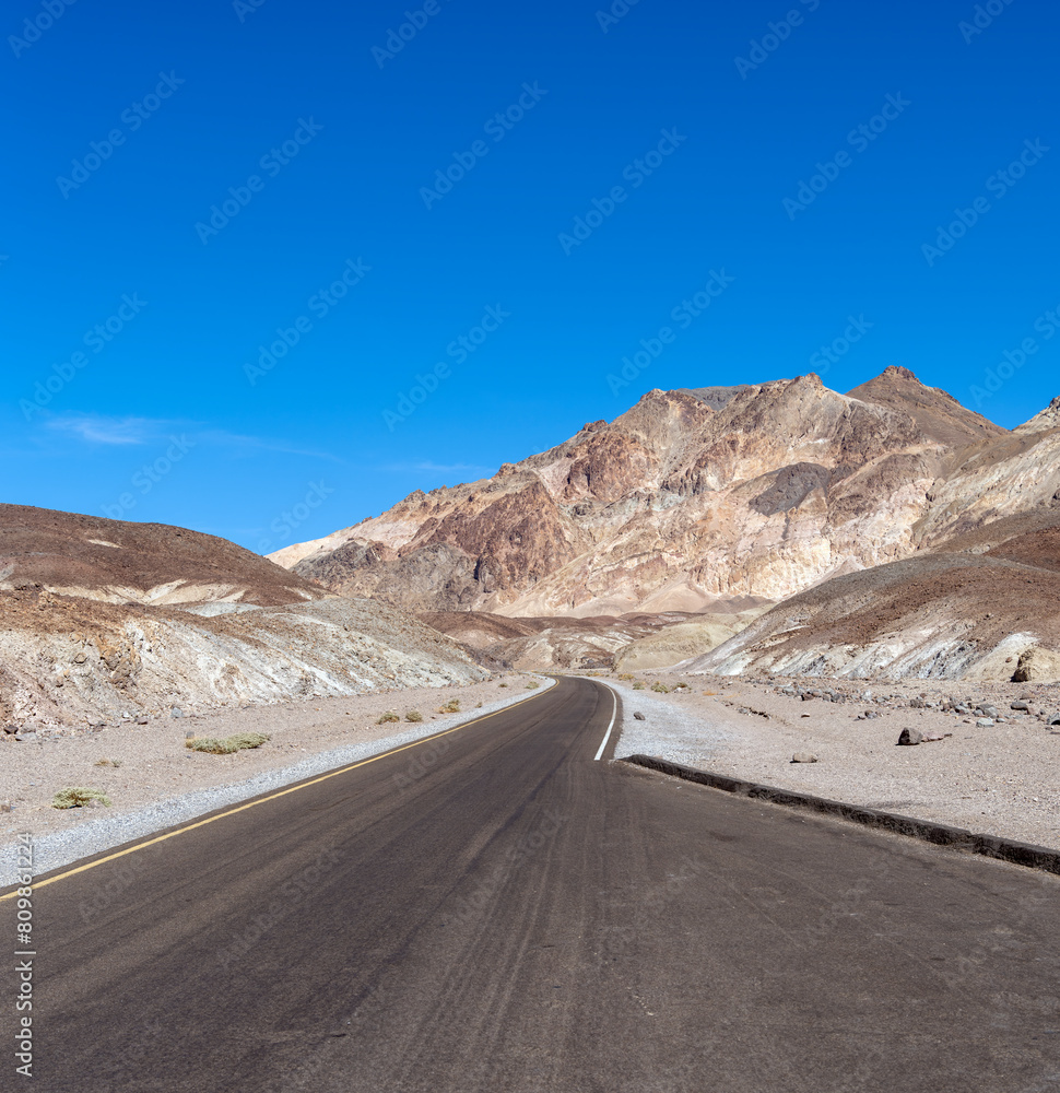 Winding road in Death Valley California with rugged Rocky Mountains.