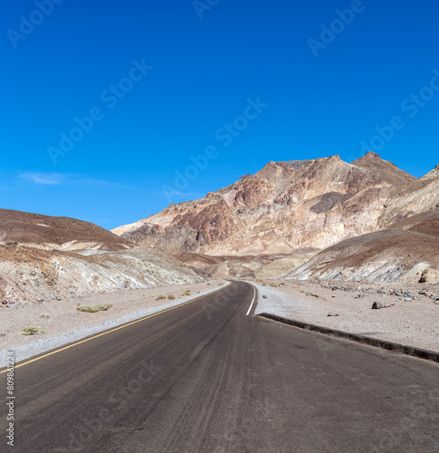 Winding road in Death Valley California with rugged Rocky Mountains.