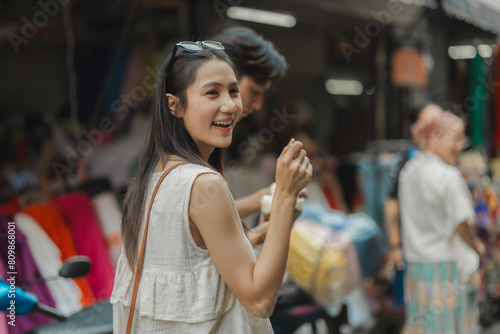 the young lovely couple is walking around traditional food market under the sun, love is showing from their face when they have conversation because they love each other, dating