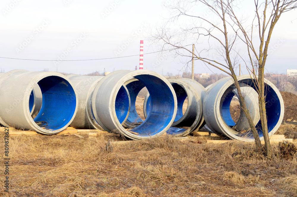 Reinforced concrete storm sewer pipes lie on a construction site Reinforced concrete storm sewer pipes lie on a construction site