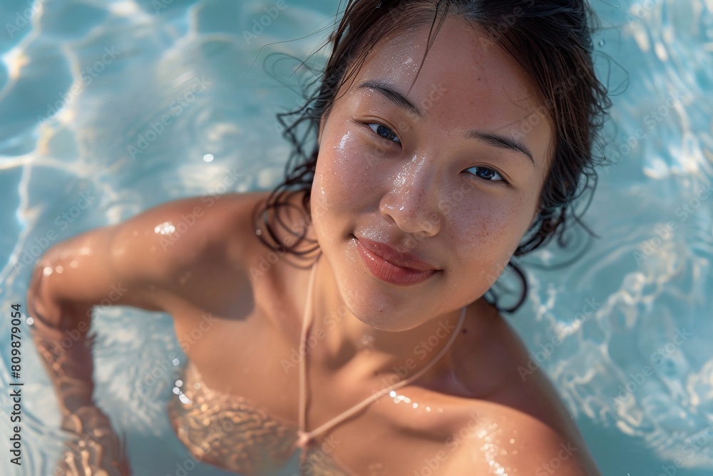 An up-close view of an Asian woman with bronzed skin, slender yet shapely, confidently stepping out of the water in a bikini An up-close view of an Asian woman with bronzed skin, slender yet shapely, confidently stepping out of the water in a bikini