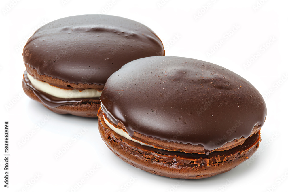 two chocolate macarons with cream filling on a white surface two chocolate macarons with cream filling on a white surface
