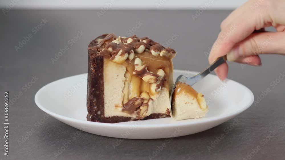 Woman eating a chocolate and caramel cheesecake with a spoon. Delicious desserts. Close up view. Woman eating a chocolate and caramel cheesecake with a spoon. Delicious desserts. Close up view.