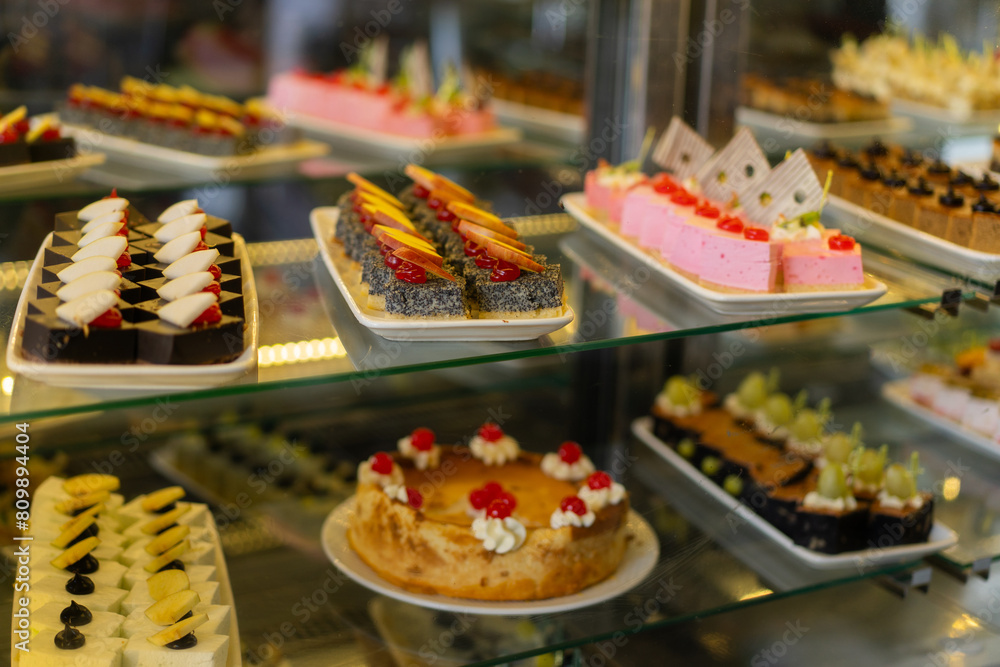 Showcase with sweets, Various desserts and cakes for sale in the pastry shop. Glass display at store bakery pastry shop. Showcase with sweets, Various desserts and cakes for sale in the pastry shop. Glass display at store bakery pastry shop.