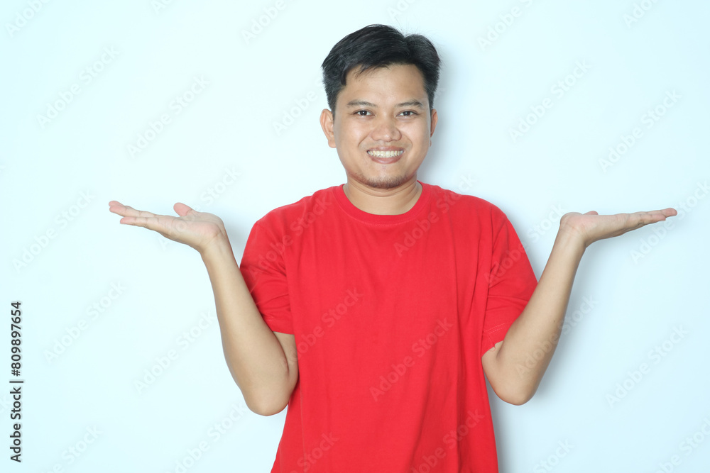 Young Asian man smiling expression while to his open both hand palm. Wearing red t-shirt Young Asian man smiling expression while to his open both hand palm. Wearing red t-shirt