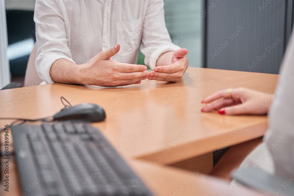 unrecognizable woman attending to a man in a clinic or at a reception desk. you can see the keyboard and mouse of the computer and the hands of a man and a woman talking. unrecognizable woman attending to a man in a clinic or at a reception desk. you can see the keyboard and mouse of the computer and the hands of a man and a woman talking.