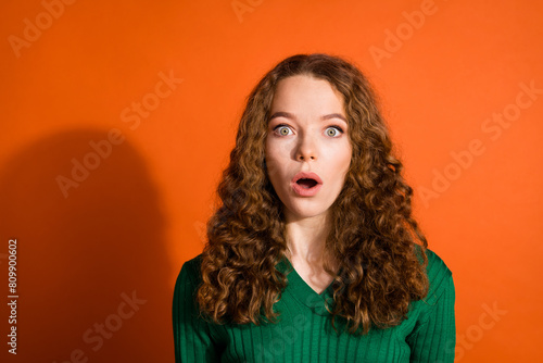 Photo of shoked ipmressed lady dressed green shirt open mouth big eyes isolated orange color background photo