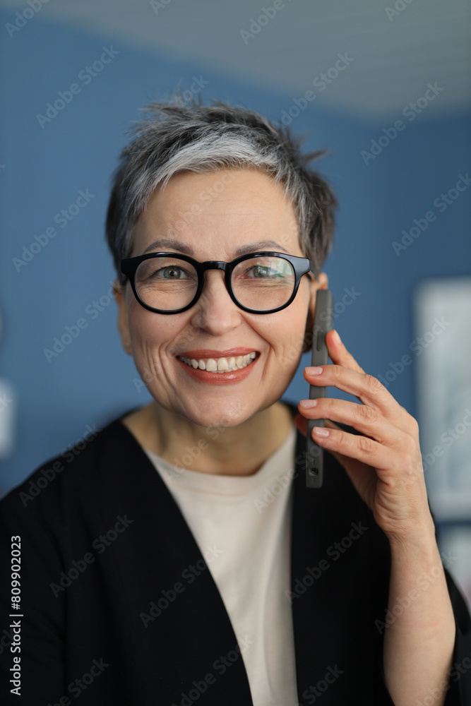 A positive senior businesswoman smiles confidently, radiating happiness and success in her portrait.