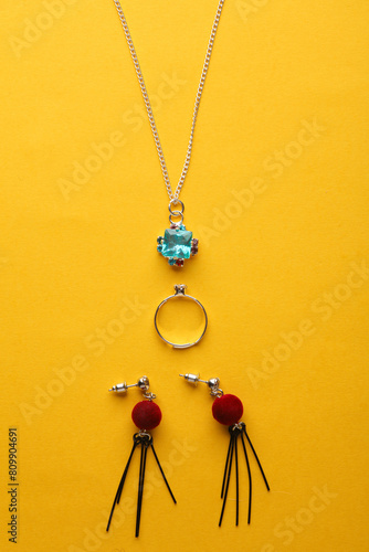 Set of jewelry on a yellow background. Pendant on a chain, ring and earrings on a yellow background. Top view. Flat lay photo