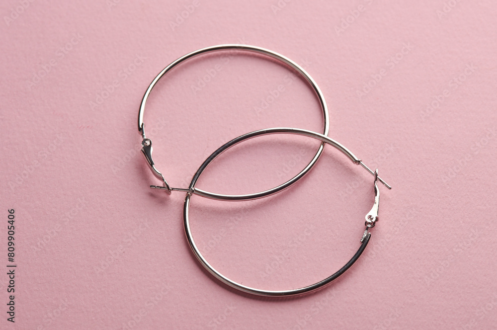 Silver hoop earrings on pink background. Women's accessories, beauty concept. Creative layout, minimalism Silver hoop earrings on pink background. Women's accessories, beauty concept. Creative layout, minimalism