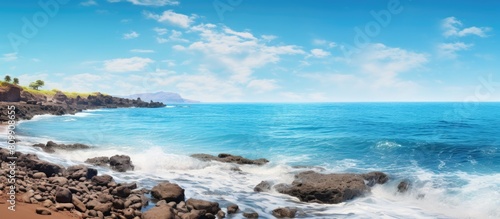 A serene beach with a rocky shore calm ocean waves and a blue sky in the background ideal for a copy space image 108 characters