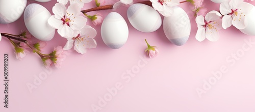 A beautiful aerial shot of Easter eggs and cherry blossom flowers with a double border against a soft pink banner background Plenty of copy space is available