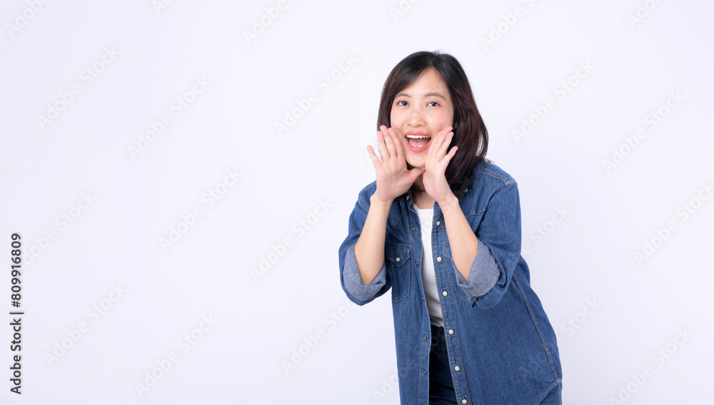Asian woman wearing denim jean is posing with a shouting gesture against a white background. Asian woman wearing denim jean is posing with a shouting gesture against a white background.