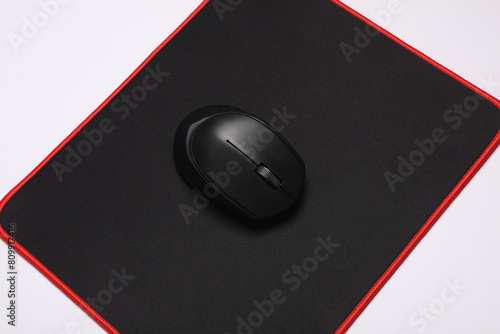 Black PC mouse with PC mouse pad on a black background