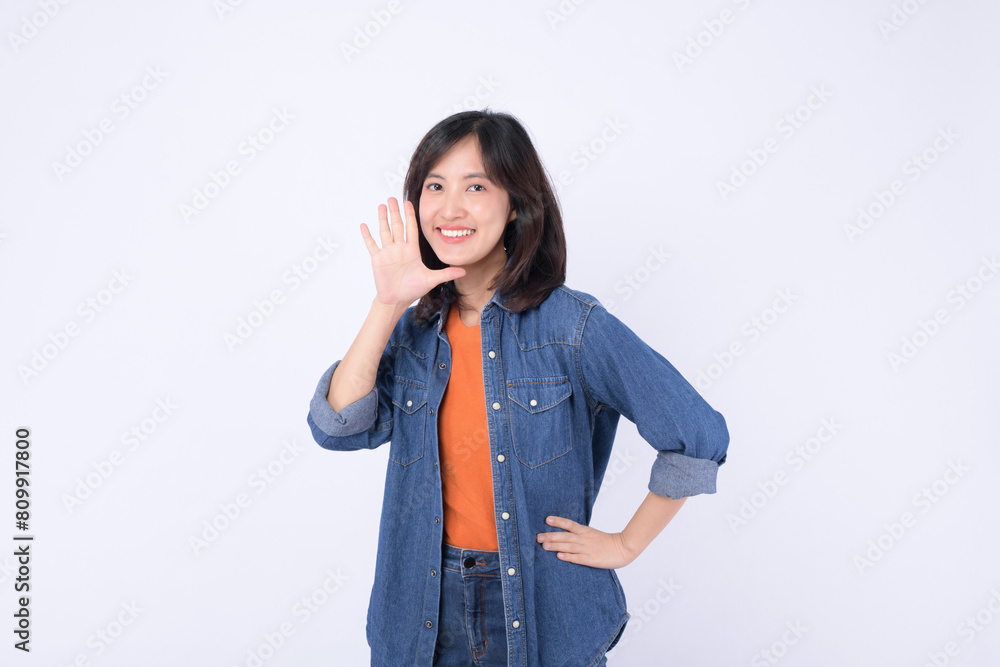 Asian woman wearing orange t shirt and denim jean is posing with a shouting gesture against a white background. Asian woman wearing orange t shirt and denim jean is posing with a shouting gesture against a white background.