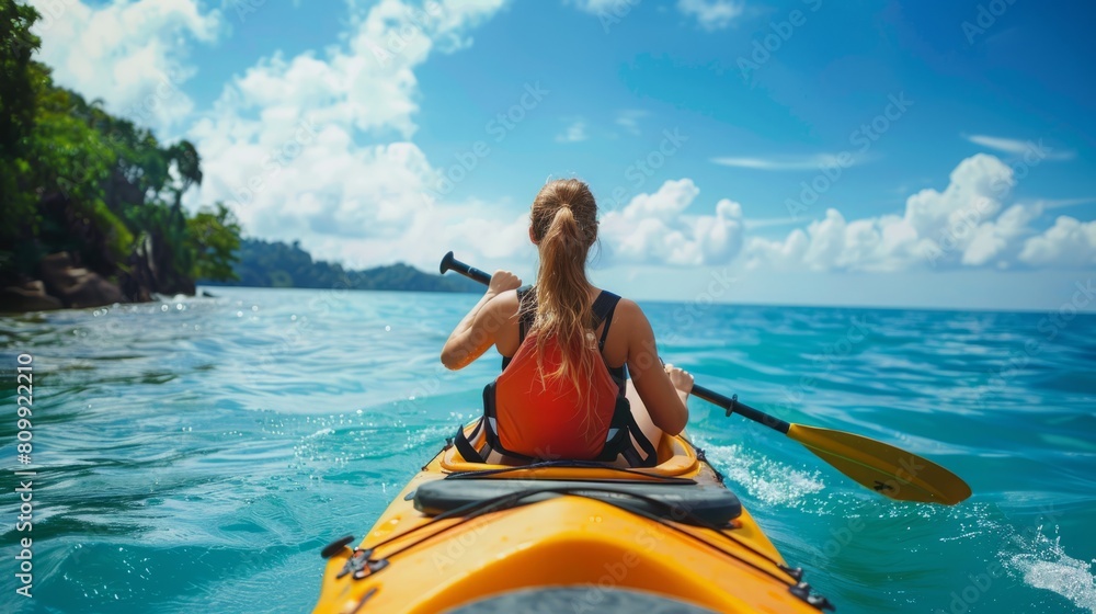 A woman is actively paddling a kayak on the open ocean.