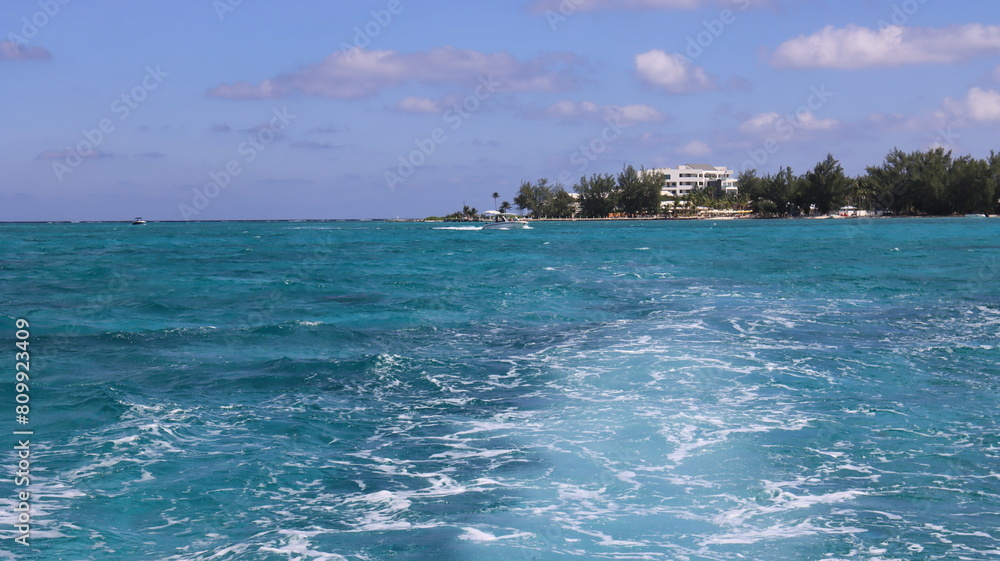 grand cayman, cayman islands from the caribbean sea tropical island vibes pristine blue turquoise sea water of the caribbean Atlantic ocean waves trees green grand cayman, cayman islands from the caribbean sea tropical island vibes pristine blue turquoise sea water of the caribbean Atlantic ocean waves trees green