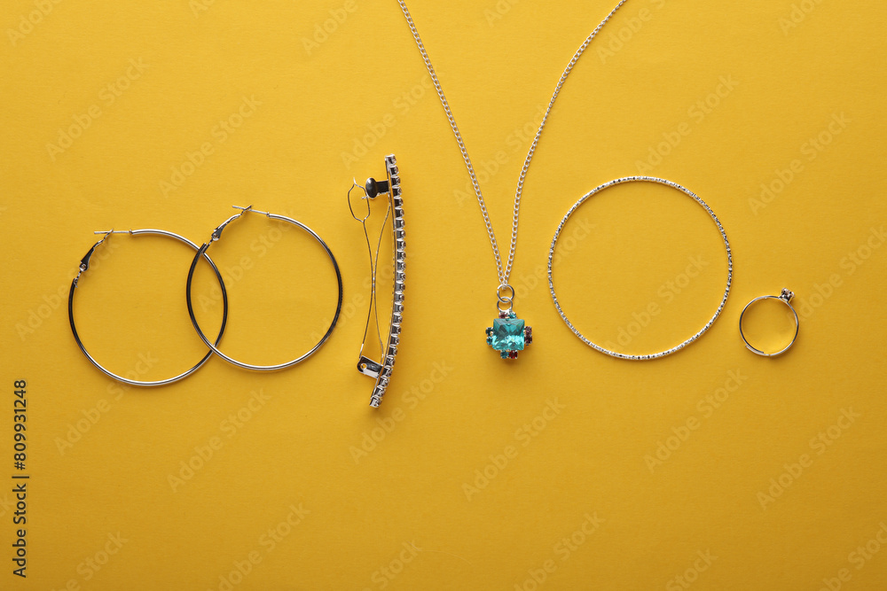 Silver jewelry accessories. Ring, bracelet, earrings, pendant, hairpin on a yellow background. Top view. Flat lay Silver jewelry accessories. Ring, bracelet, earrings, pendant, hairpin on a yellow background. Top view. Flat lay