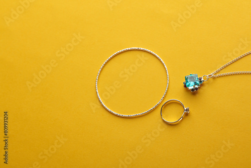 Jewelry silver bracelet, ring and pendant on a yellow background photo