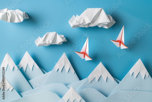 Back to school origami paper project of hang glider over white snowy mountains, clouds, blue sky photo