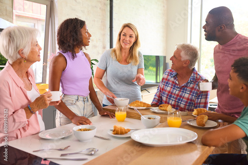 Three Generation Family Indoors At Home Preparing And Eating Breakfast Together