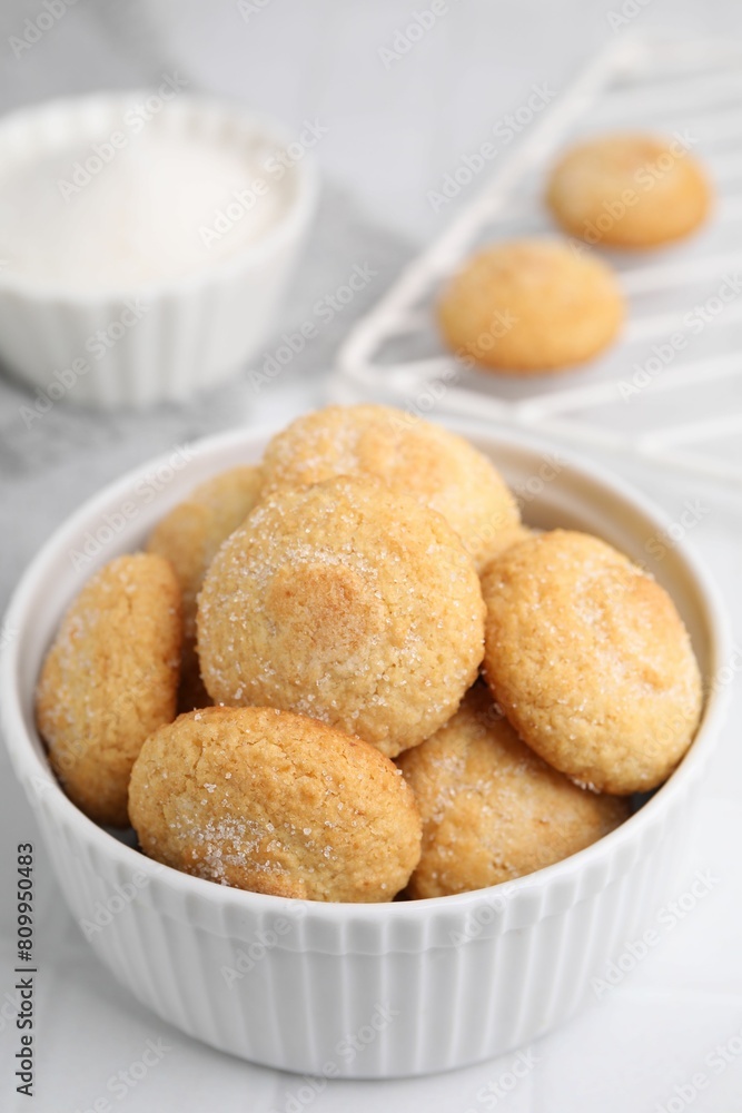 Tasty sugar cookies in bowl on white tiled table, closeup