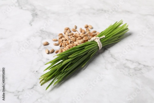Sprouts of wheat grass and seeds on white marble table, closeup