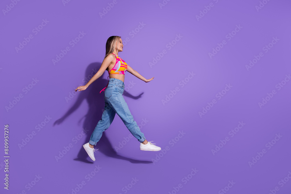 Photo of carefree active cute girl wear trendy clothes look empty space isolated on purple color background