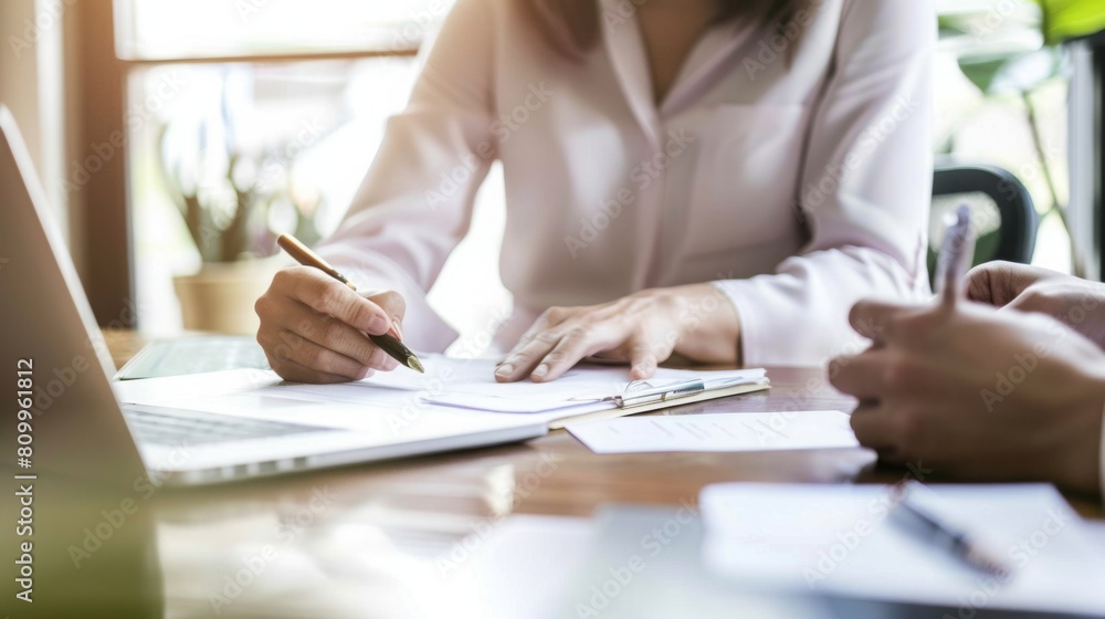 Two professionals engaged in a discussion and writing notes during a daytime work meeting. Two professionals engaged in a discussion and writing notes during a daytime work meeting.