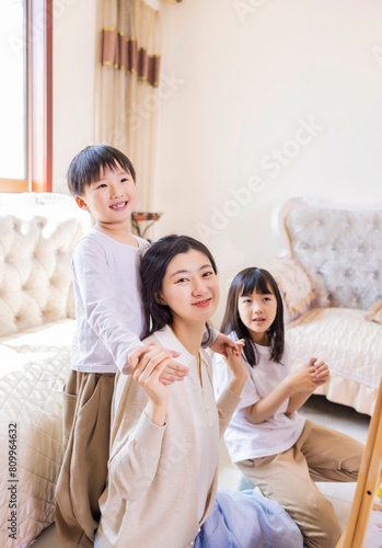 In the living room, the young mother accompanied the two siblings to play games