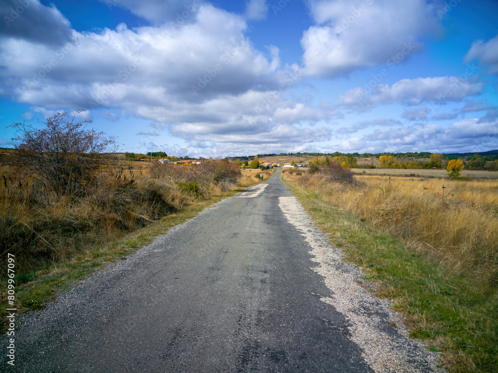 Road with newly repaired asphalt leading to a rural town in autumn, Val Porquero, León, Spain 