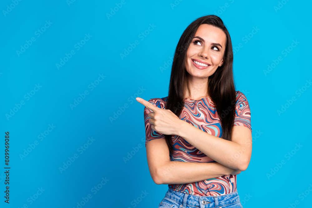 Photo portrait of pretty young girl point look empty space wear trendy colorful clothes isolated on blue color background Photo portrait of pretty young girl point look empty space wear trendy colorful clothes isolated on blue color background