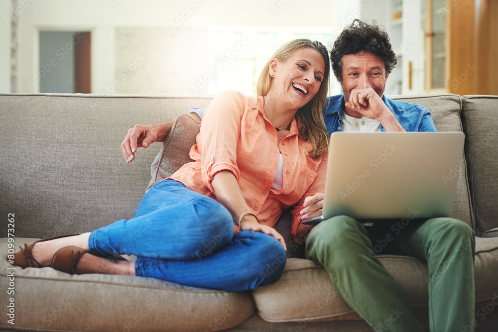 Mature, couple and laughing with laptop on couch for comedy movie, funny series or streaming service in home. People, technology and comic video on sofa with relax, bonding or entertainment in lounge Mature, couple and laughing with laptop on couch for comedy movie, funny series or streaming service in home. People, technology and comic video on sofa with relax, bonding or entertainment in lounge