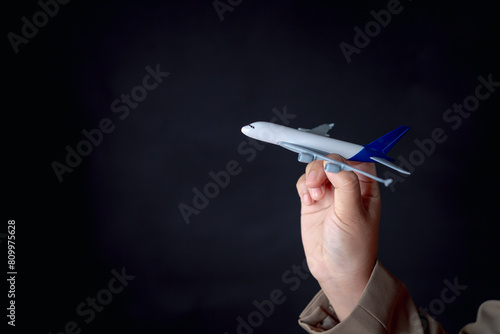 Photo of a businessman holding a model airplane at the airport, depicting the concept of air travel and aviation