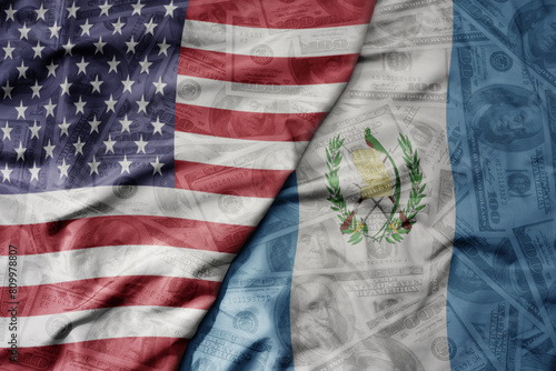 big waving colorful flag of united states of america and national flag of guatemala on the dollar money background. finance concept. photo