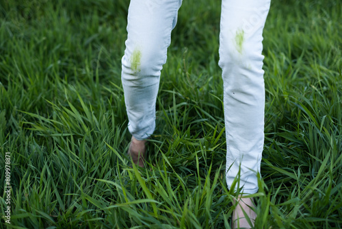 Close up dirty grass stains on white clothes. An unrecognizable person with green knees on a green background. Spoiled clothes. Daily life dirty stain.outdoors.